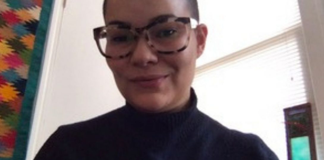 Christine Hier, smiling wearing a glasses and a black, long-sleeved turtleneck sweater.
